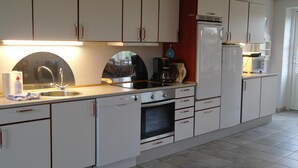 Une cuisine avec des armoires blanches, un évier, une cuisinière et un réfrigérateur.