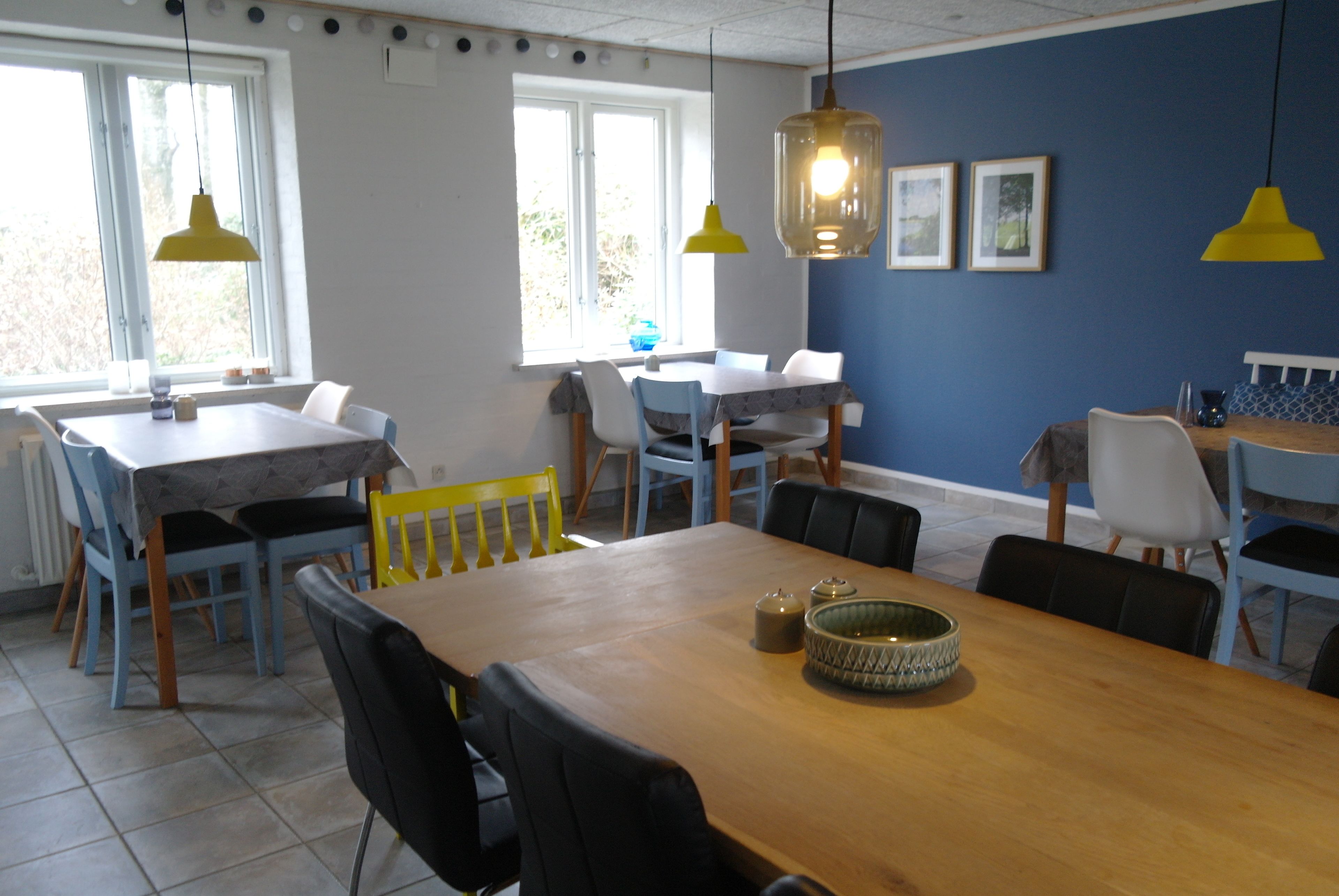 Een eethoek met een houten tafel, stoelen en gele hanglampen.