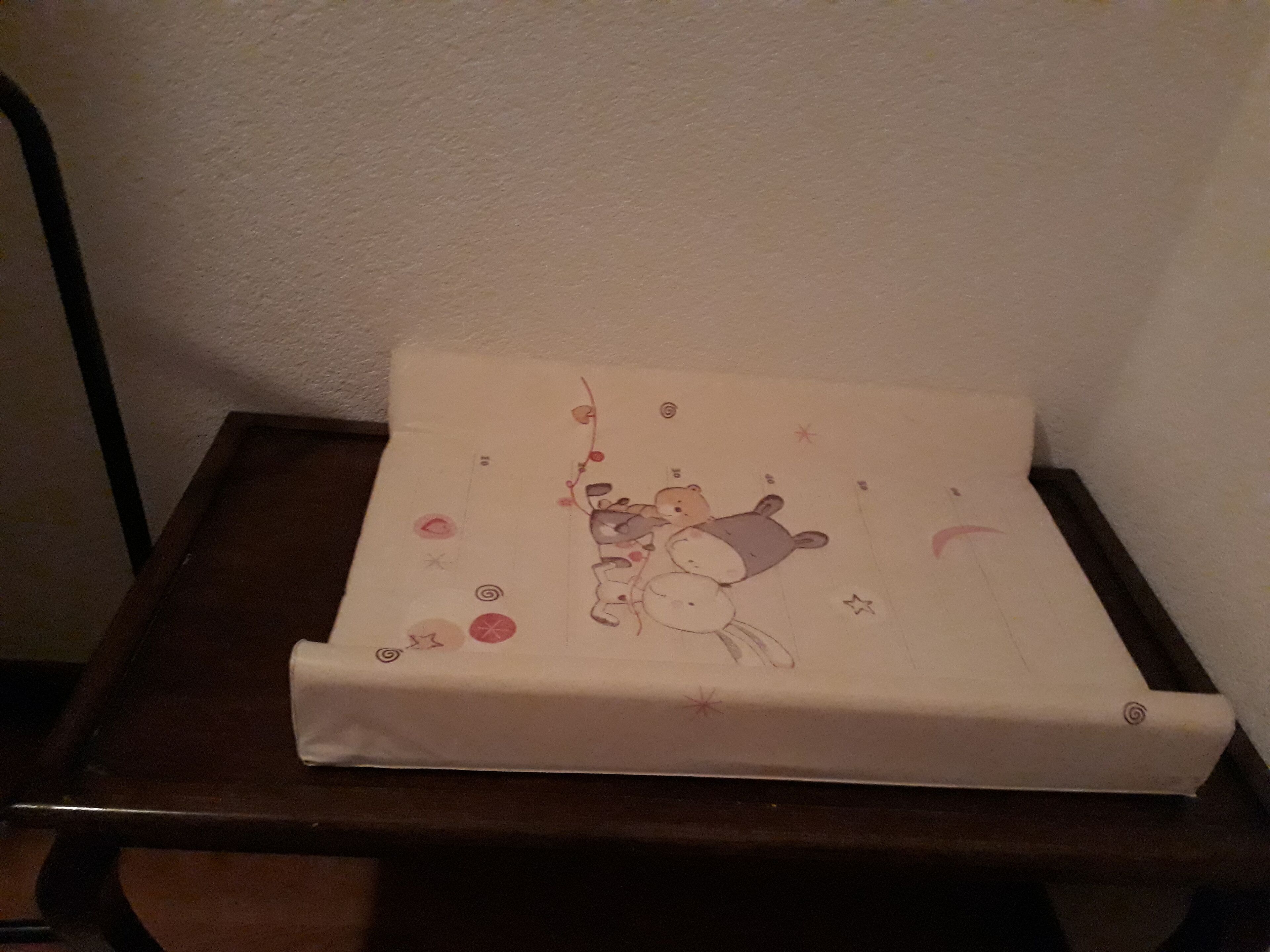Une petite table en bois foncé, surmontée d’un coussin blanc orné d’une illustration d’ours.