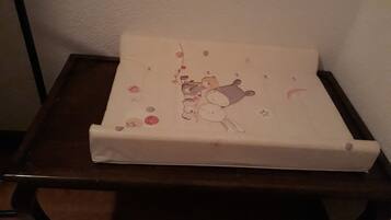 Une petite table en bois foncé, surmontée d’un coussin blanc orné d’une illustration d’ours.