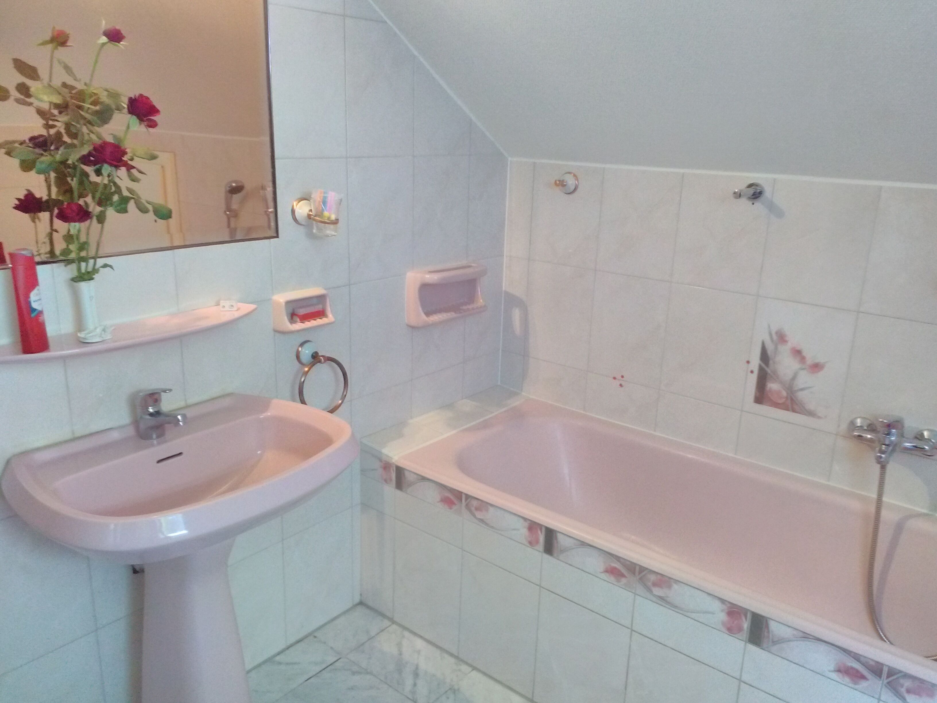 Un baño con lavamanos, espejo, bañera y retrete.