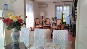 Un coin repas avec une table en verre, des chaises à motifs floraux et un vase rempli de fleurs.
