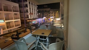 Un comedor con mesa y sillas, un estante con objetos y vista a la calle por la noche.