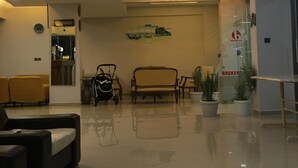 Un vestíbulo de hotel con recepción, zona de estar y una escalera que conduce al piso superior.