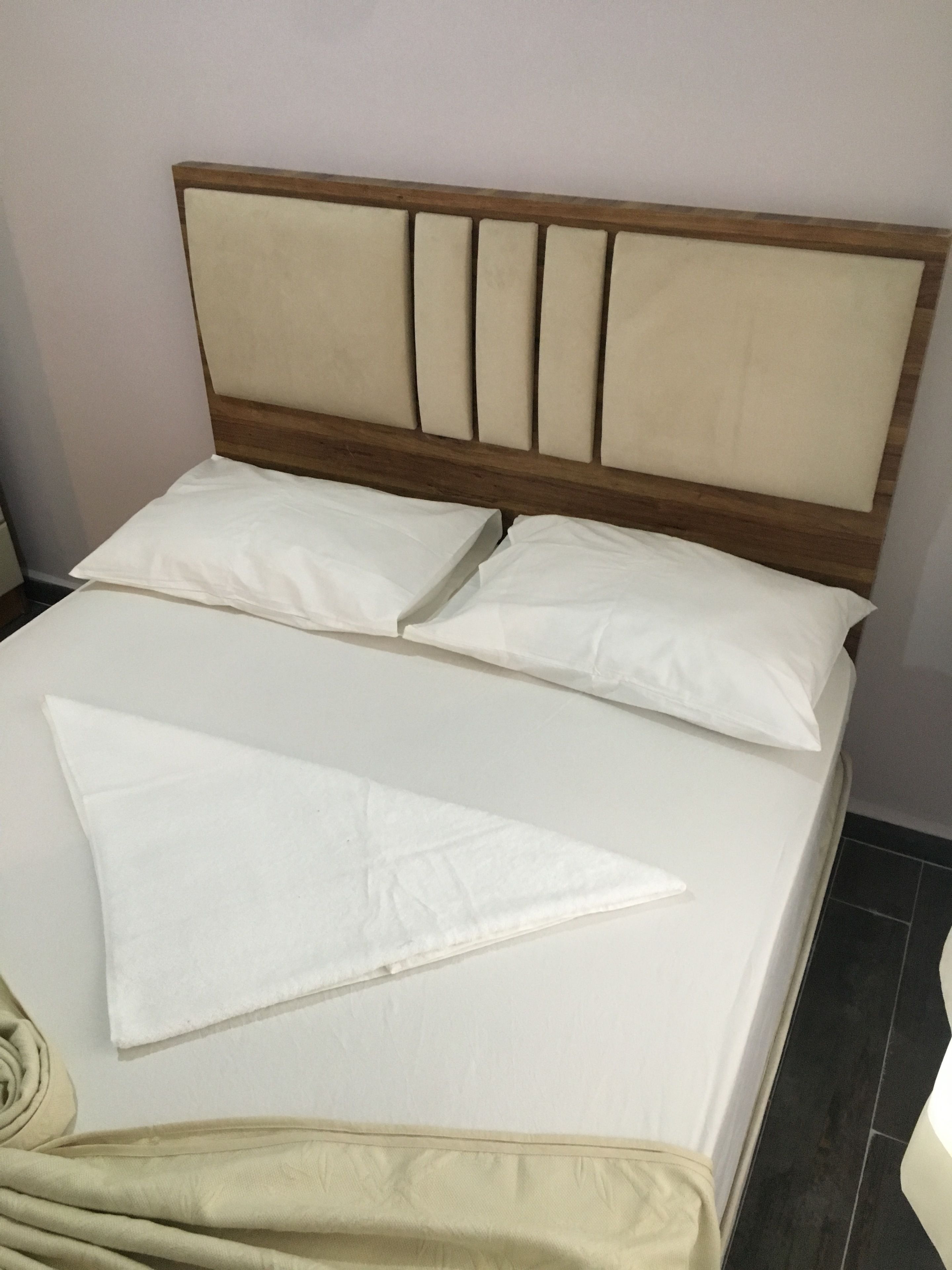 Una cama con cabecera de madera y ropa de cama blanca.