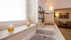 A kitchen with a double sink, a window, and candles on the windowsill.