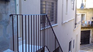 A narrow staircase with a metal railing leading to a landing.