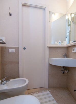 Un baño con un lavamanos blanco, un espejo y una puerta.