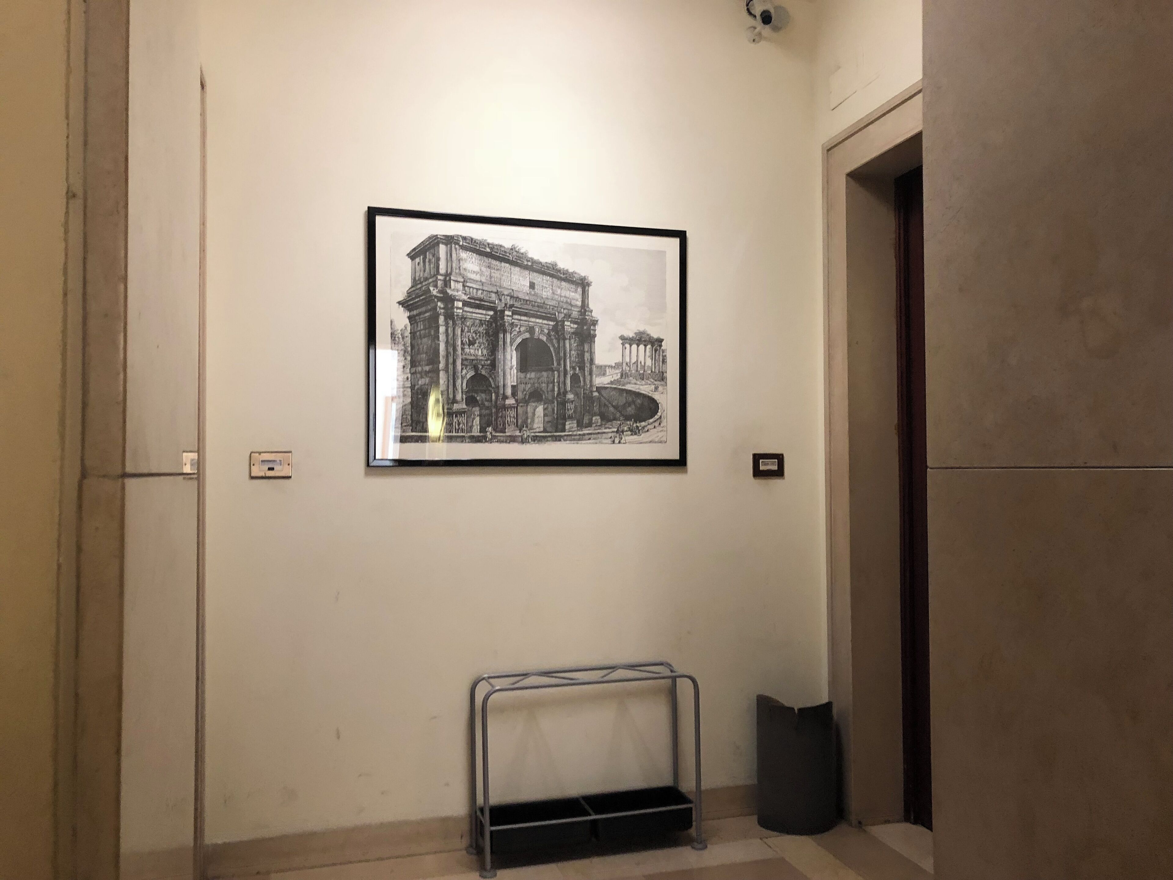 A framed black and white photograph of an ancient archway on a wall in a hallway.