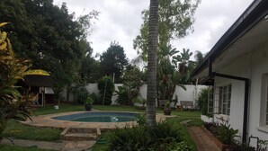 Un patio trasero con piscina, un sendero de piedra y diversas plantas.