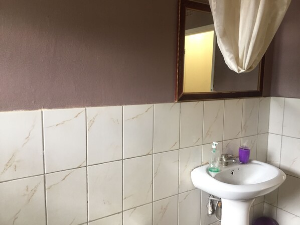 A bathroom with a white sink, a mirror, and a towel hanging on the wall.