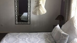 Un dormitorio con cama, dosel colgante, espejo y ventana con cortinas.