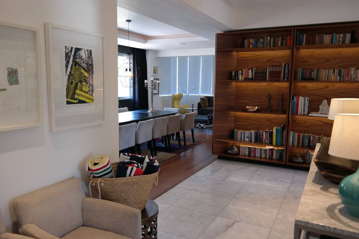 A spacious living area with a dining table, chairs, a bookshelf, and a sofa.