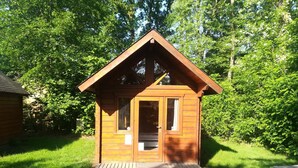 A small wooden cabin with a pitched roof, a front door, and a small porch. - Camping Baalse Hei (Turnhout)