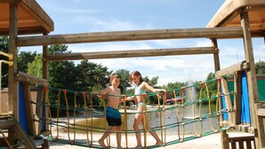 A wooden play structure with a rope bridge and a sandy ground. - Camping Baalse Hei (Turnhout)