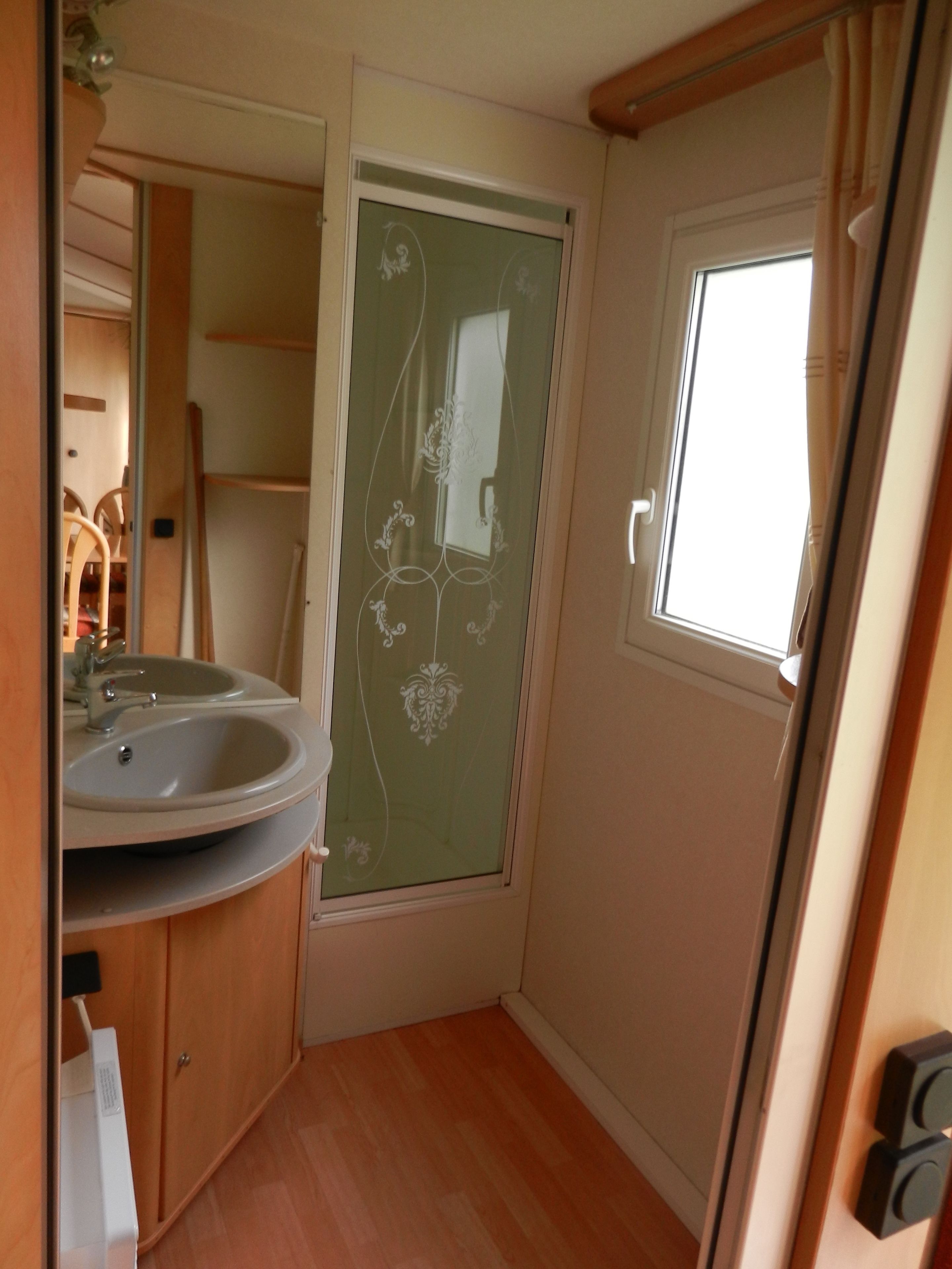 A compact bathroom with a sink, mirror, and a window.