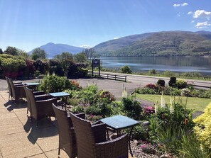 A patio with wicker furniture and a view of a lake and mountains. - Hillview guest house (Fort William)