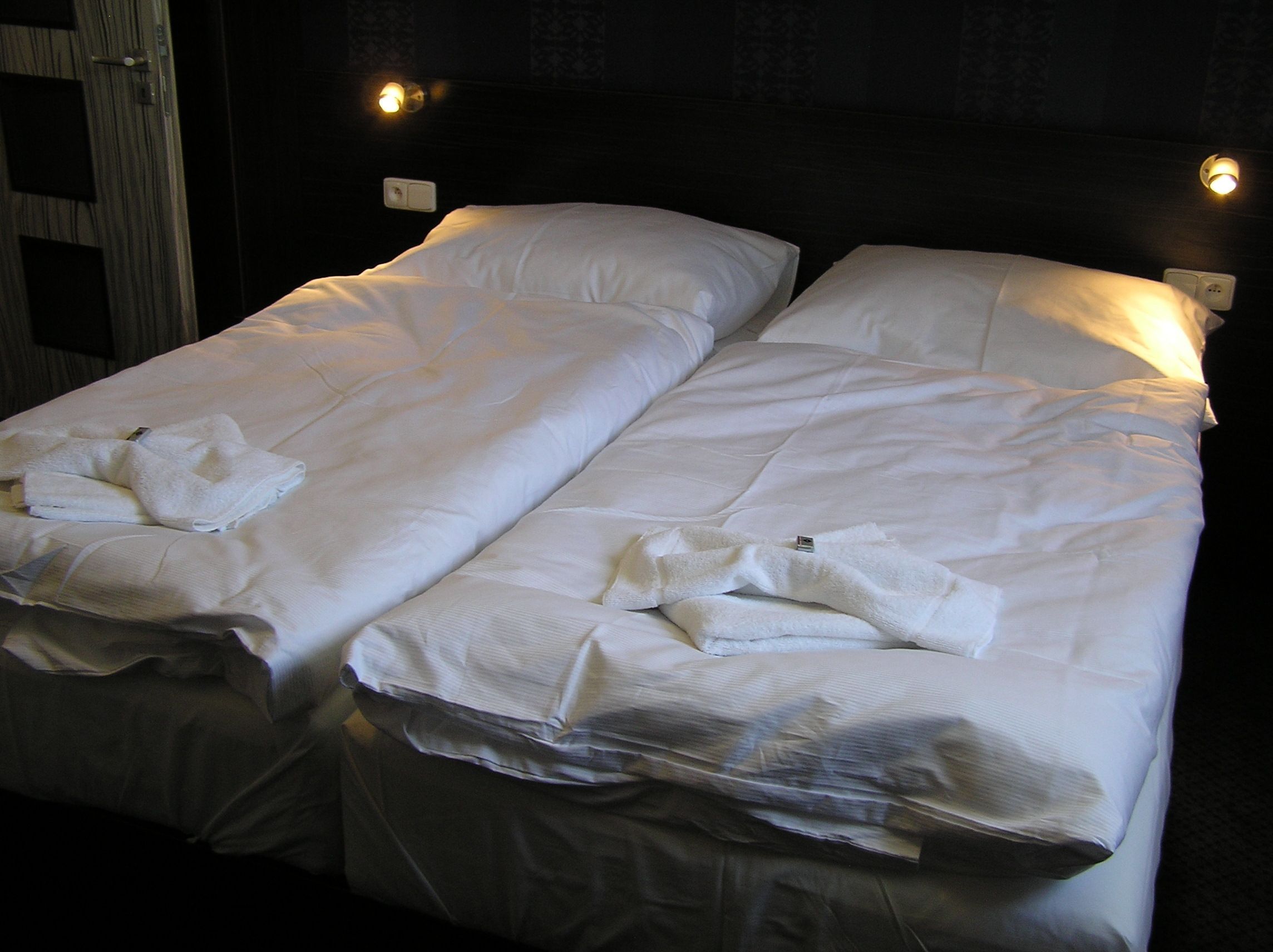 A hotel room with two single beds, each with white linens and towels.