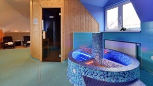 Un cuarto de sauna con un jacuzzi de azulejos, paredes de madera y una ventana.