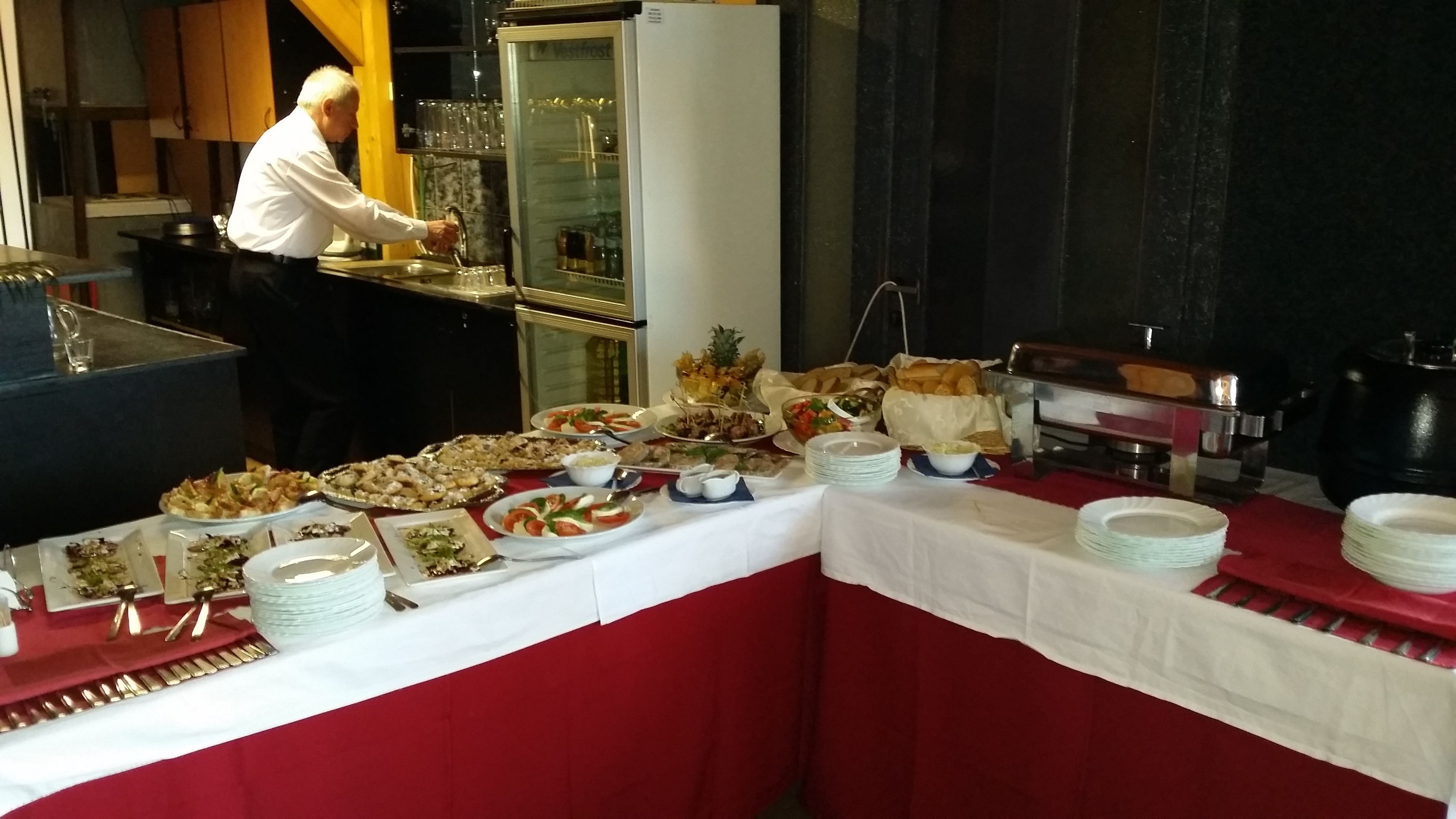 Montaje de bufé con diferentes alimentos y una persona lavando platos.
