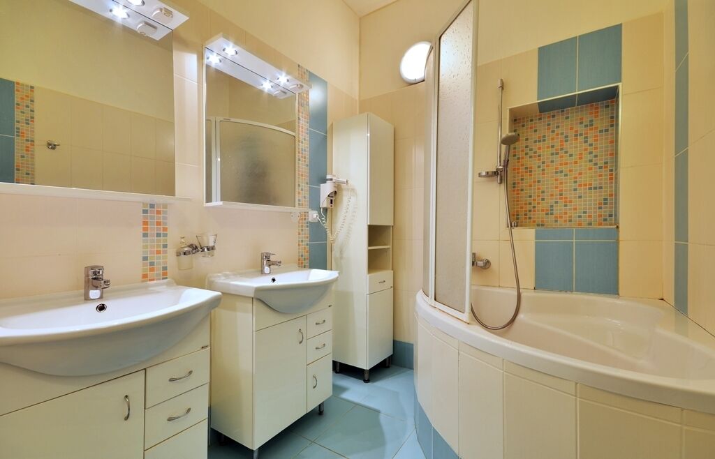 Un baño con dos lavamanos, una bañera y una ducha.