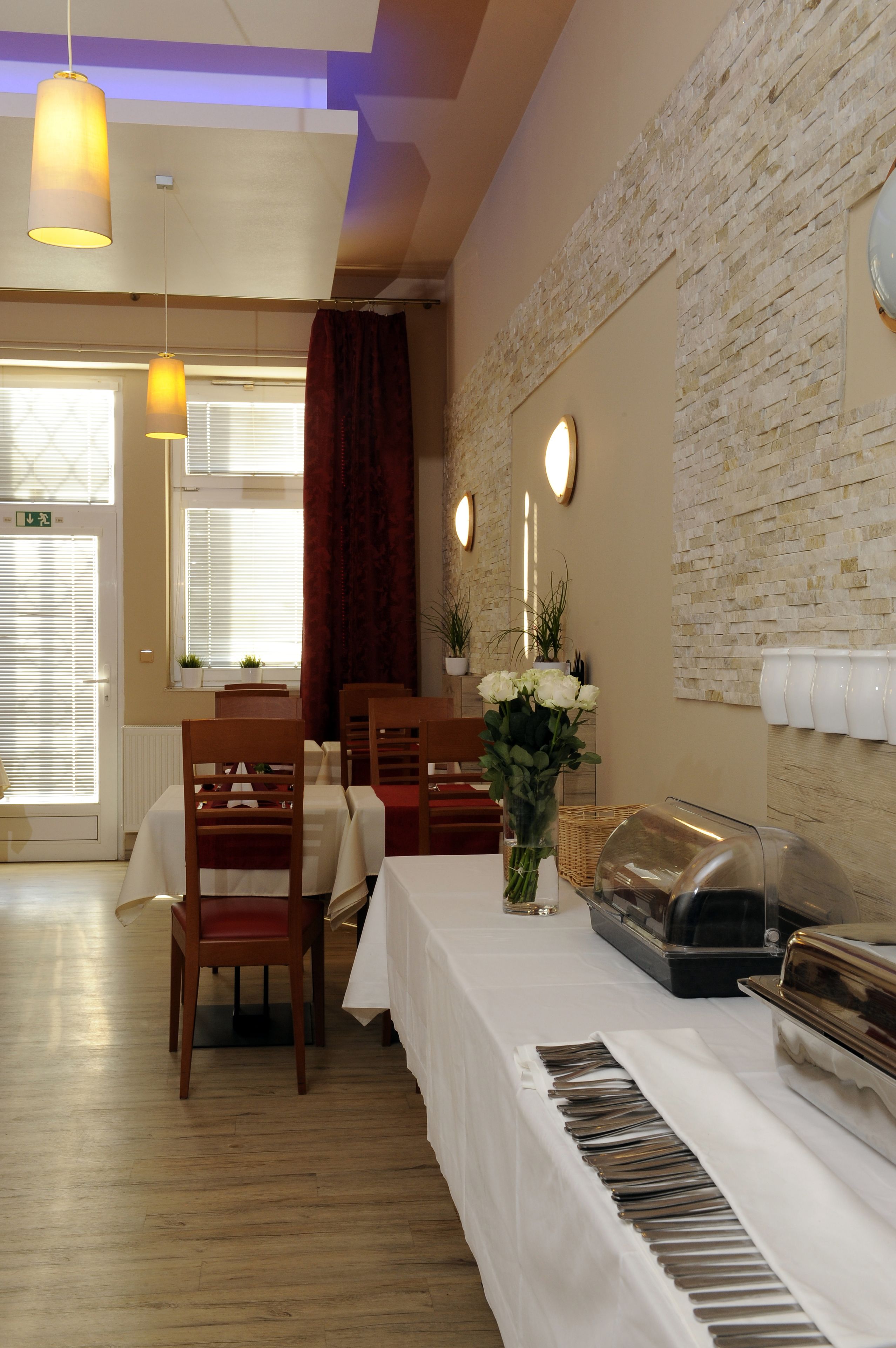A dining area with wooden chairs and tables, a piano, and a buffet setup.