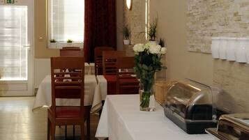 A dining area with wooden chairs and tables, a piano, and a buffet setup.
