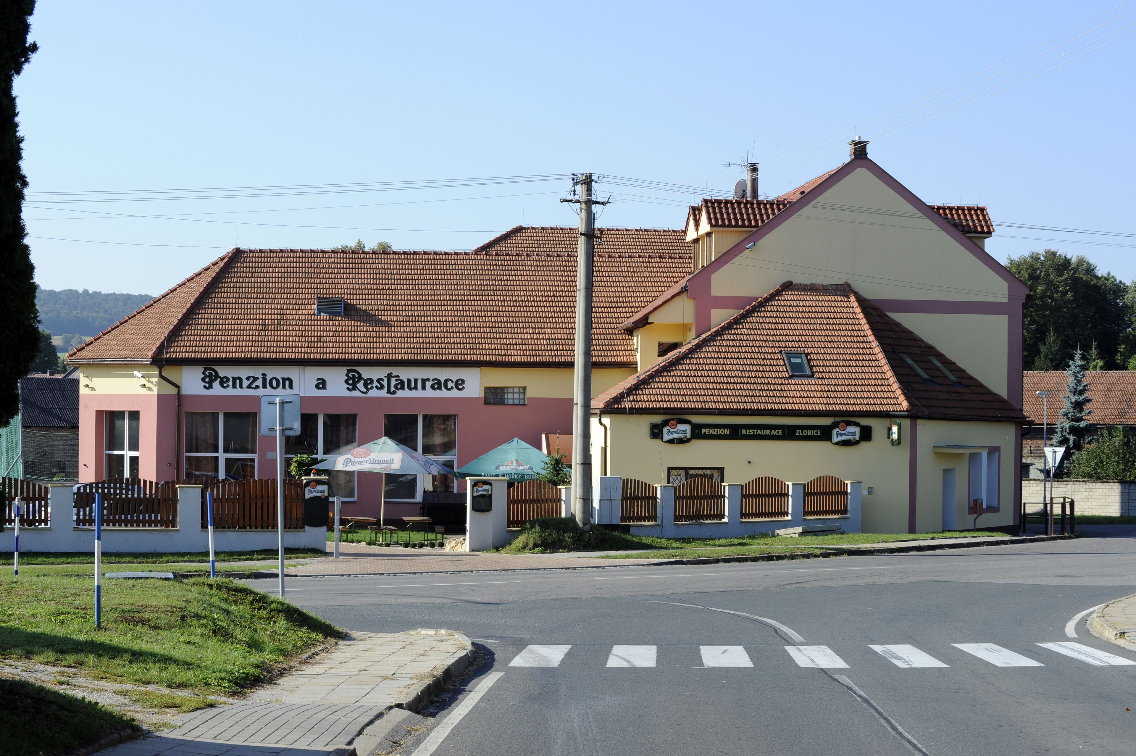 A building with a sign reading "Pension a Restaurant" and a smaller sign for "Pension Zlobice".