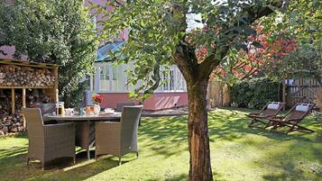 Un patio con mobiliario de mimbre, una mesa con bebidas y un árbol en el centro.