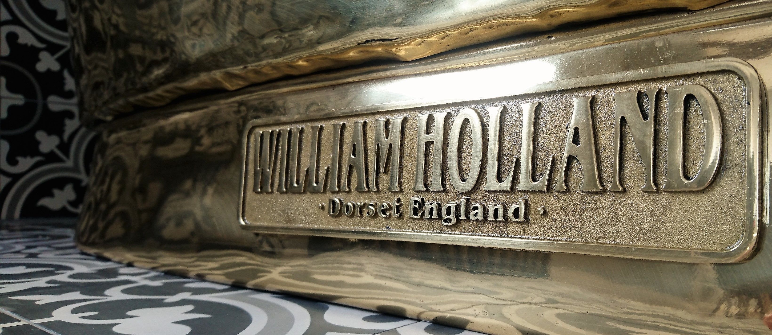 A metal plaque with the inscription "WILLIAM HOLLAND, Dorset England".