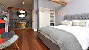Un dormitorio con una cama grande, vigas de madera, una chimenea y un armario.