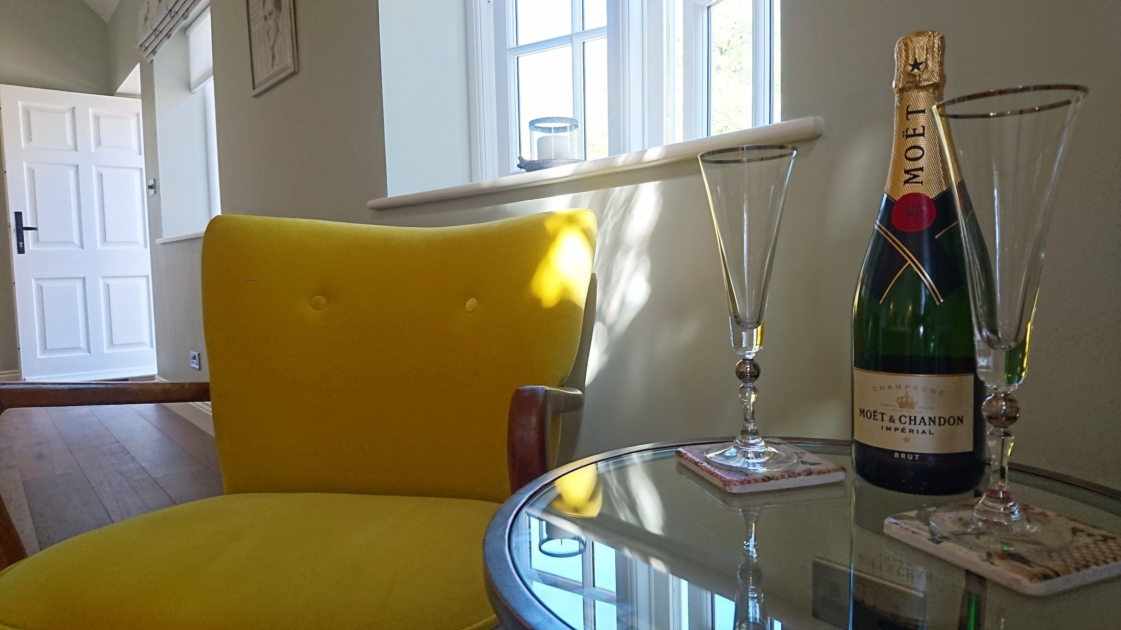 Ein gelber Sessel, ein Glastisch mit einer Flasche Moët & Chandon Champagner und einem Glas.