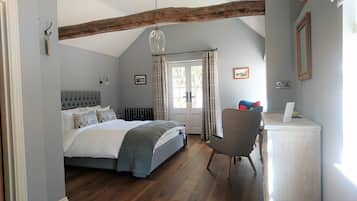 Een slaapkamer met een bed, een stoel, een bureau, een radiator en een raam met gordijnen.
