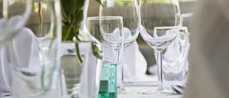A table set for a meal with clear glassware and a centerpiece of red flowers.