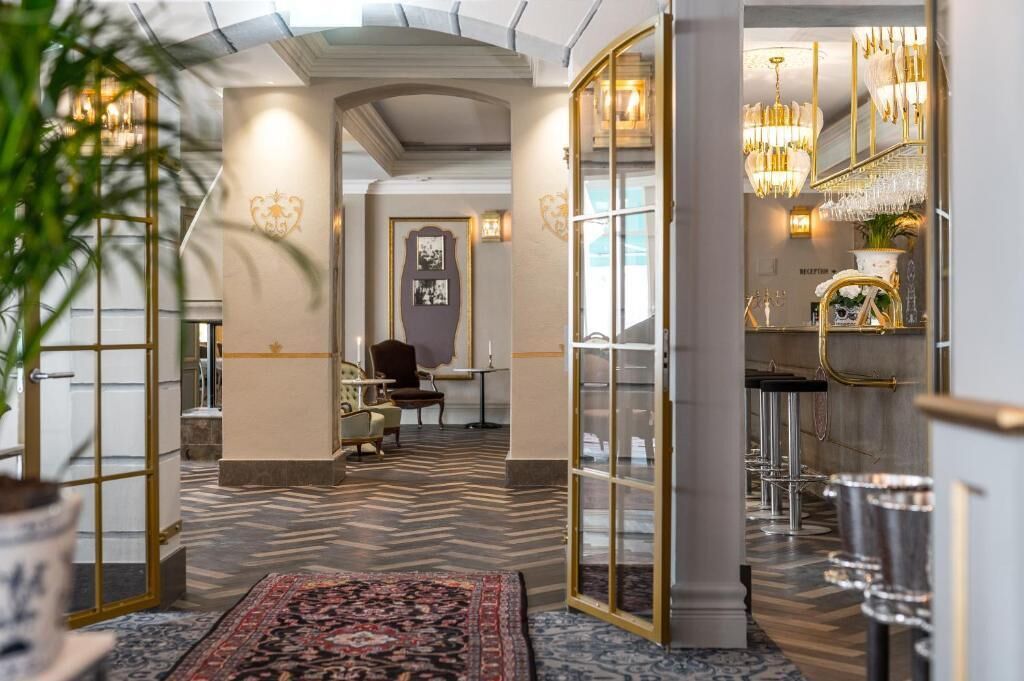 En hotellobby med en storslagen trappa, en receptionsdisk och en bardel.