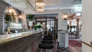 A bar area with a marble countertop, black barstools, and a chandelier. - Söderköpings Brunn (Soderkoping)