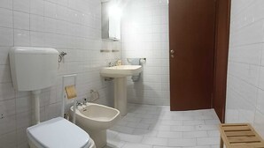 Un baño con inodoro, bidé, lavabo y espejo.