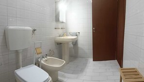 Un baño con inodoro, bidé, lavabo y espejo.