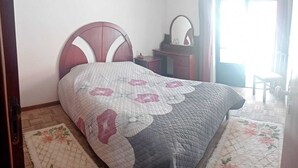 Un dormitorio con cama, cómoda, espejo y silla.