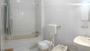 Un baño con bañera, inodoro, bidé y lavabo.