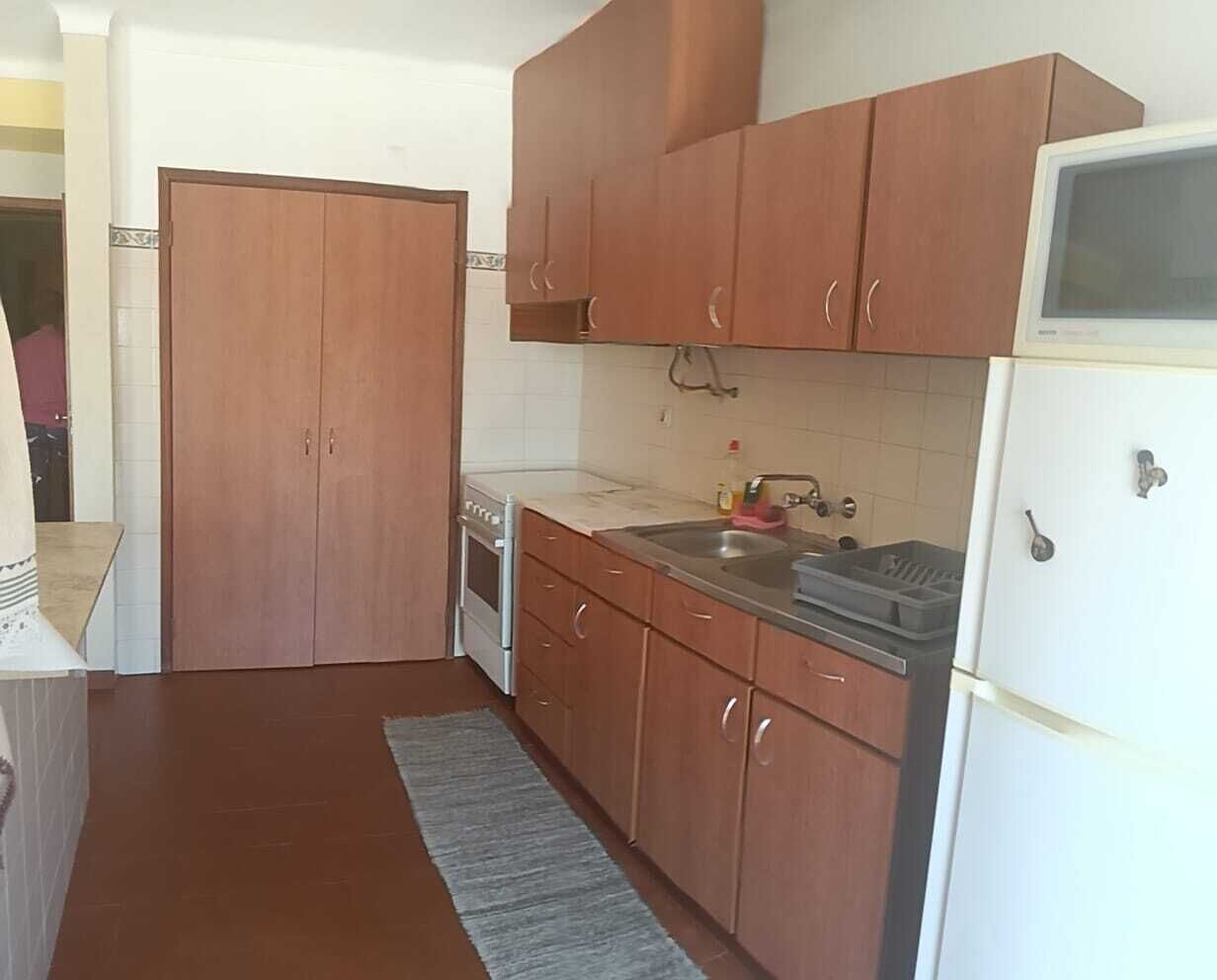 Una cocina con armarios de madera, un refrigerador blanco, una estufa y un fregadero.