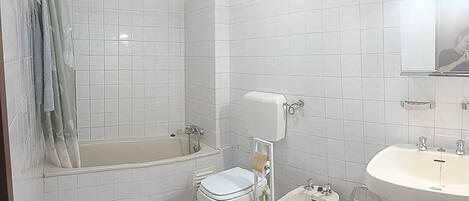 Un baño con bañera, inodoro, bidé y lavamanos.