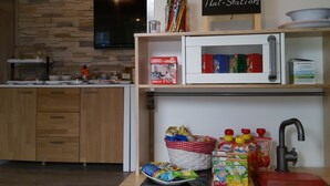 A kitchen with a stone wall, a microwave, a chalkboard menu, and various food items on the counter. - Hotel Garni Haus Sonneneck (Thale)