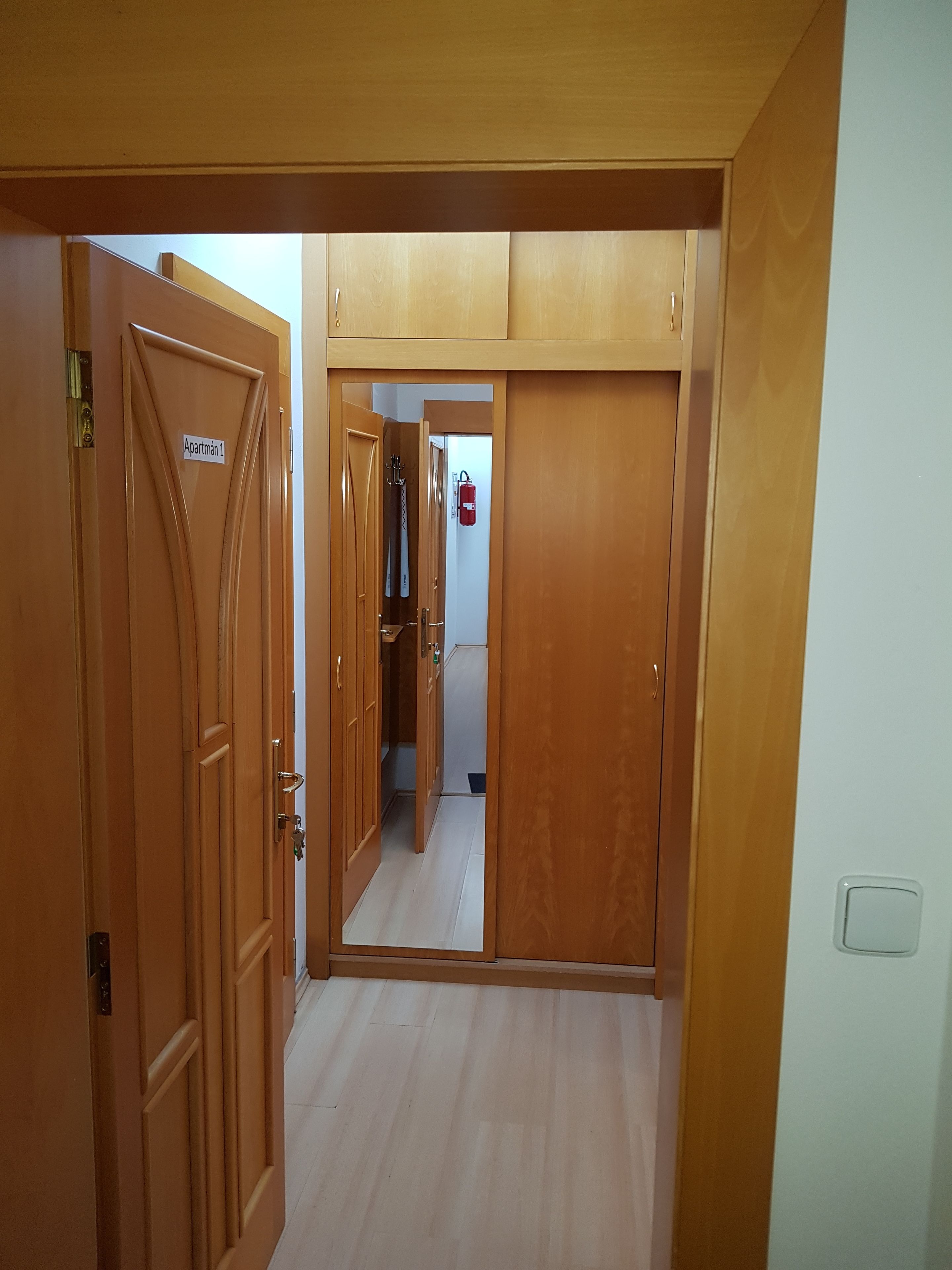 A hallway with wooden doors, one labeled "Apartman 1".
