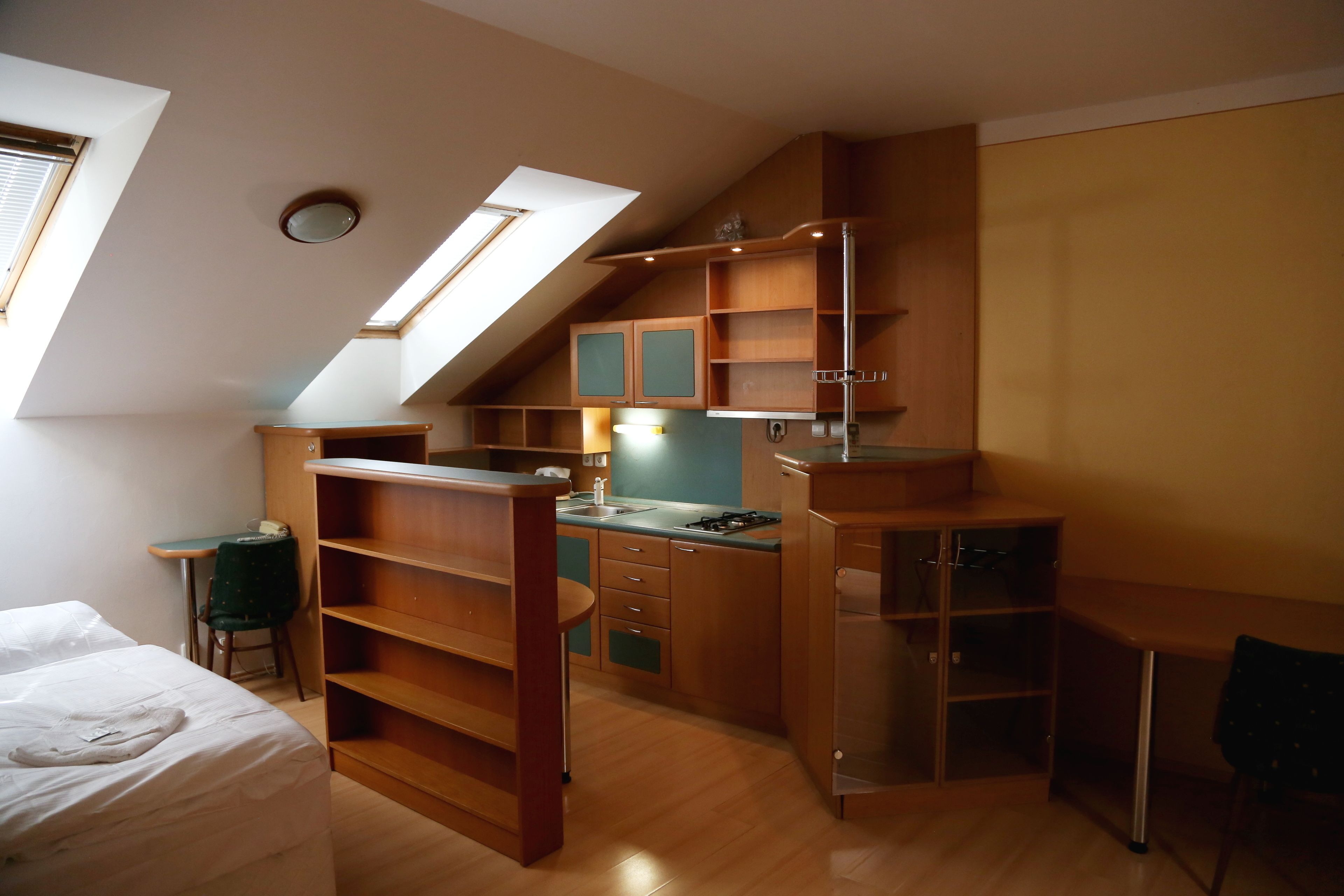 A compact room with a lofted sleeping area, a kitchenette, and a desk.