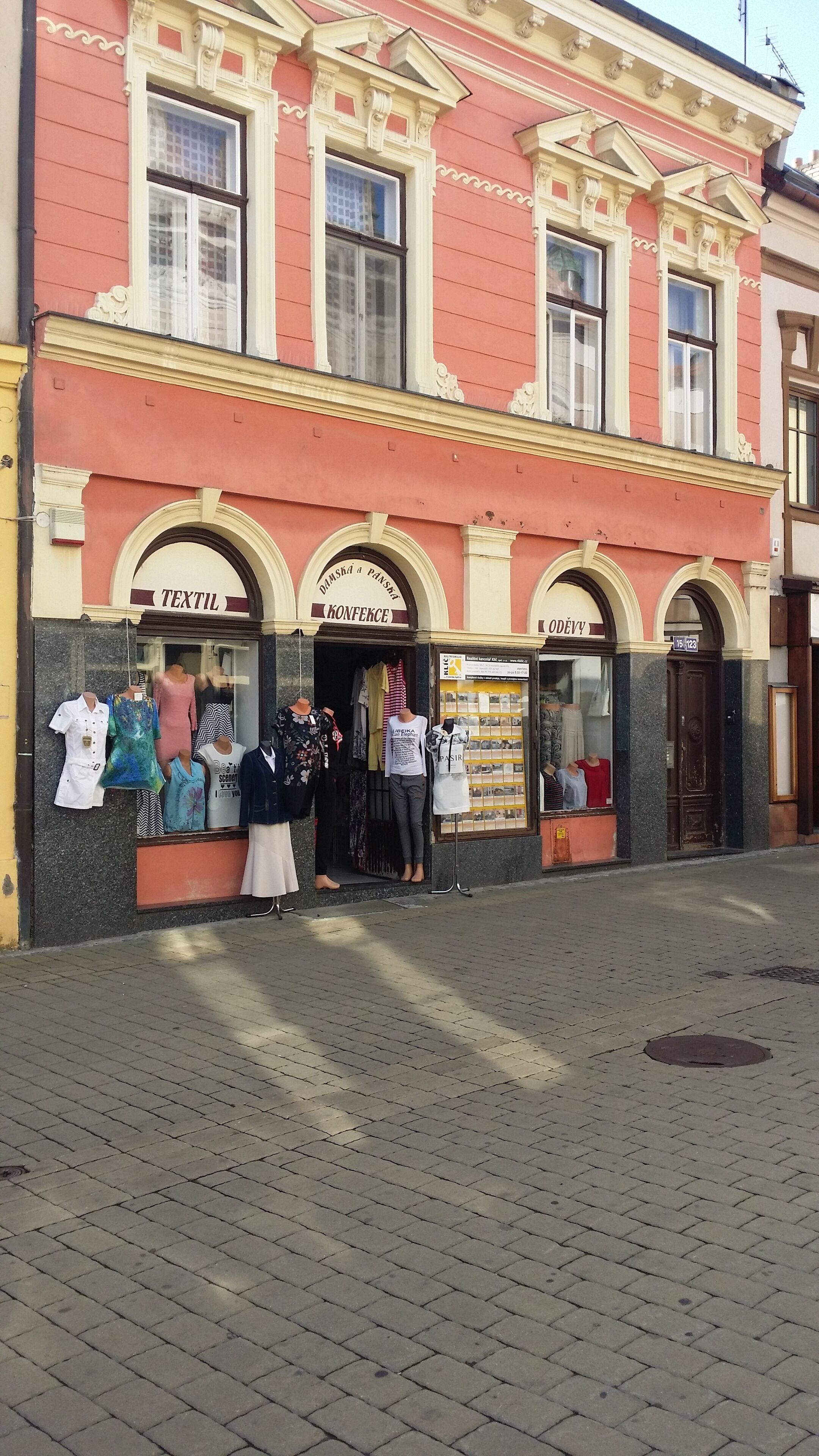 A building with a storefront displaying mannequins in various outfits.