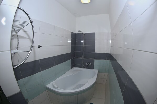 A bathroom with a bathtub, a shower, and a towel rack.