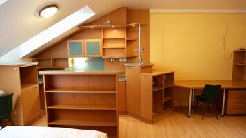Ein kompakter, aufgeräumter Raum mit eingebauten Holzbögen, einem Schreibtisch und einem Stuhl, der durch eine geneigten Decke und ein Dachfenster gekennzeichnet ist.