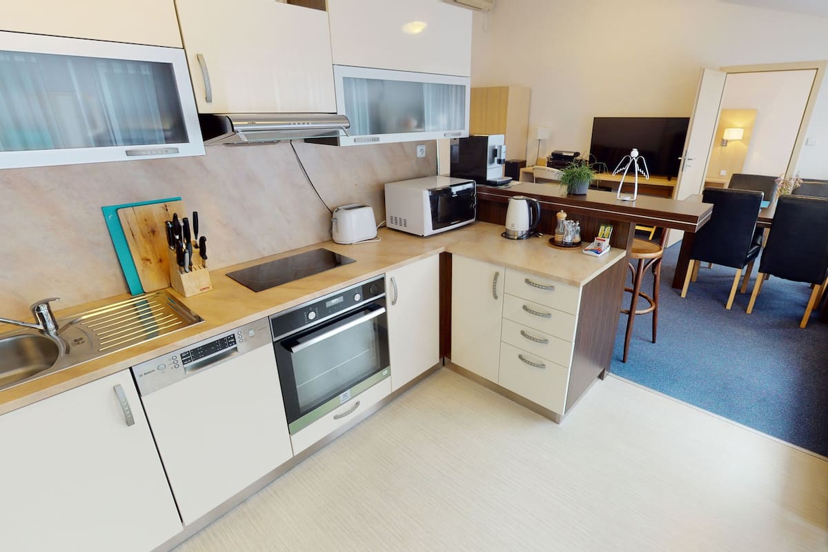 A compact kitchen with a dishwasher, oven, microwave, and a small dining area with a table and chairs.