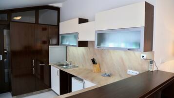A modern kitchen with dark wood cabinets, a stainless steel sink, and a built-in microwave.